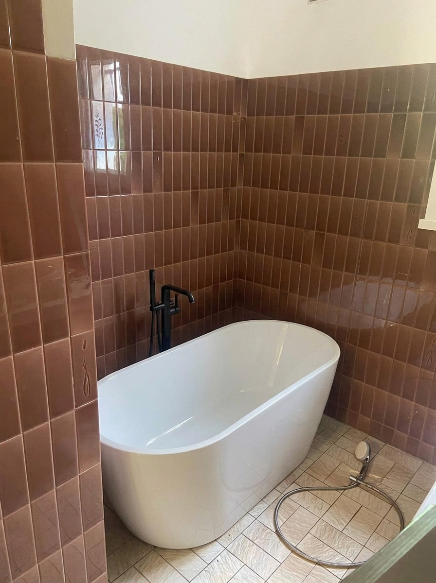 Baignoire îlot blanche de forme ovale avec robinet au sol dans une salle de bain rénovée